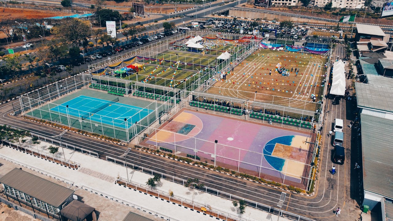 Aerial shot of colorful sports complex with tennis, basketball courts, and running tracks.