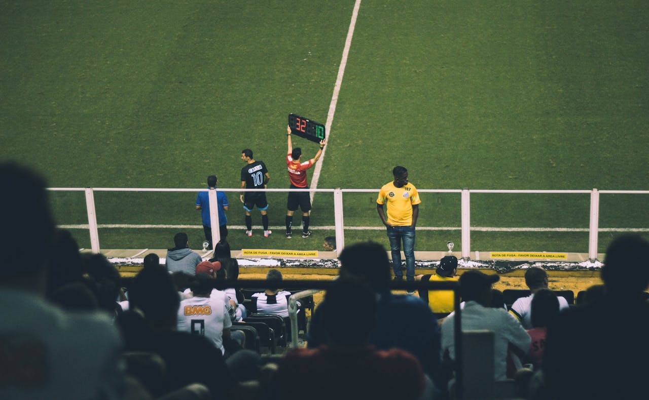 Soccer player substitution during a match at a stadium with an engaged audience.